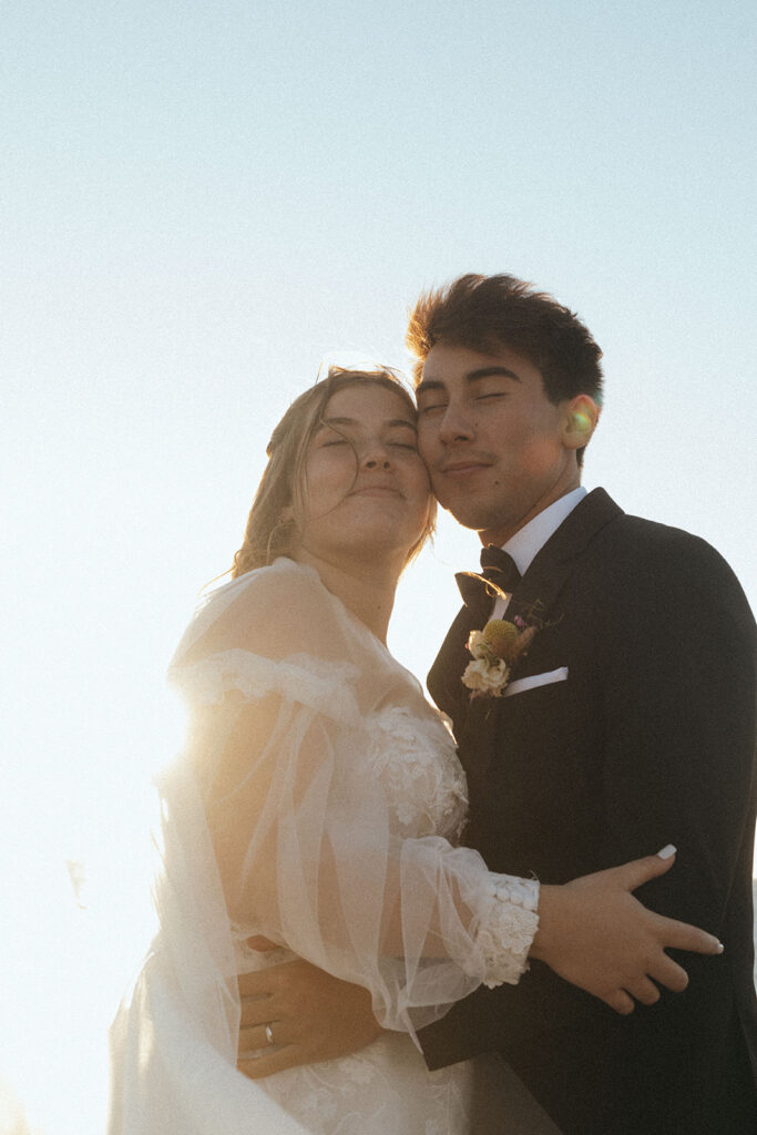 couple embraces at California coast sunset wedding