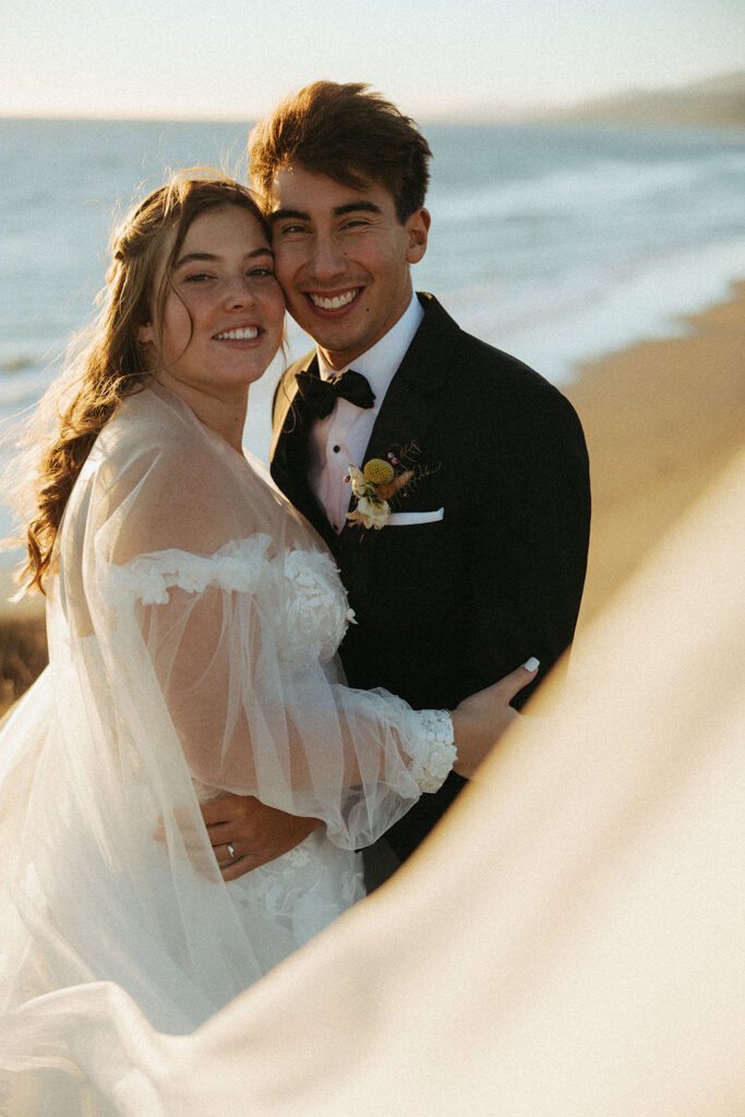 couple embraces on overlook at California coast sunset wedding