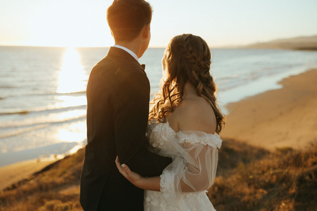 wedding couple stands overlooking California sunset