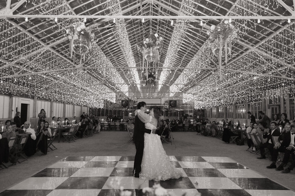 couple dances under twinkle lights at greenhouse wedding reception