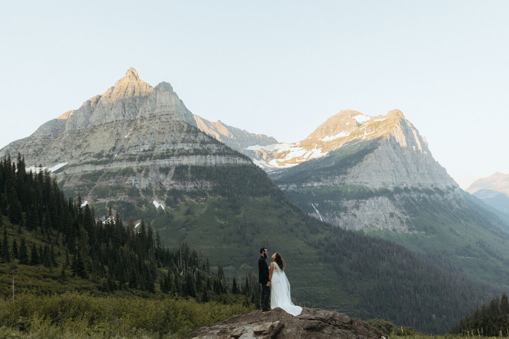 couple stands on rock in front of mountain at Glacier National Park wedding