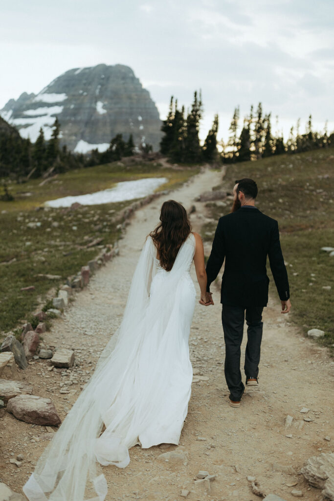 couple walks holding hands at Glacier National Park wedding