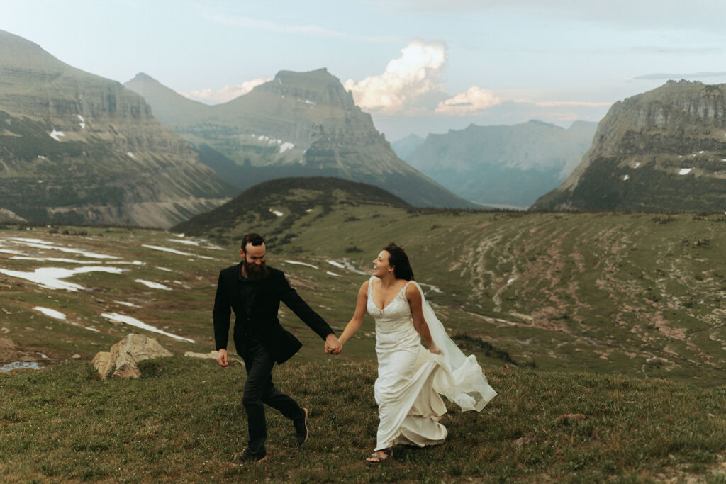 couple runs through field with mountains in background at adventure elopement