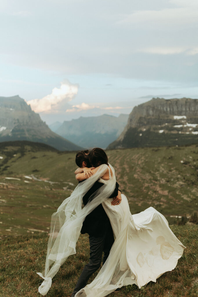 couple embraces with wedding dress in wind at Glacier National Park wedding