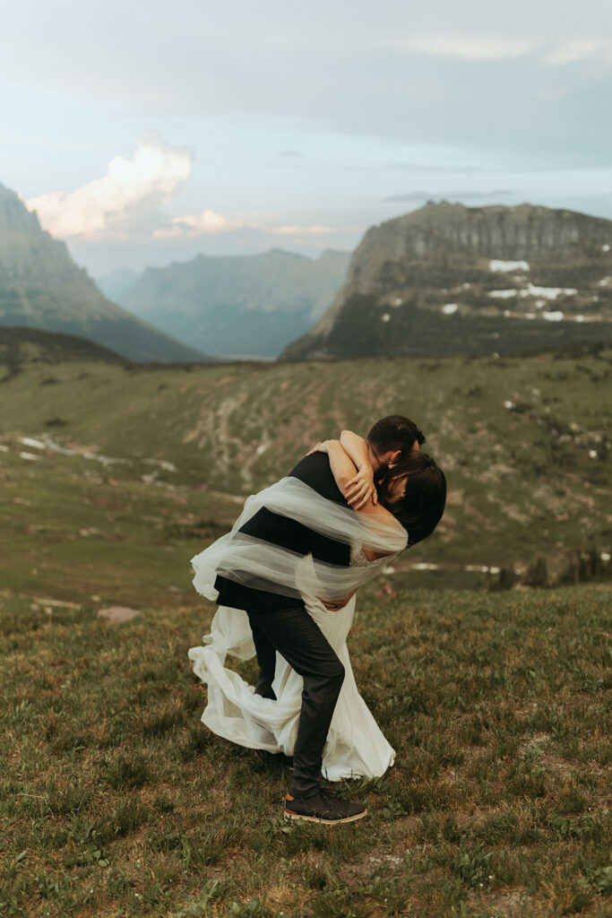 couple embraces with wedding dress in wind at Glacier National Park wedding