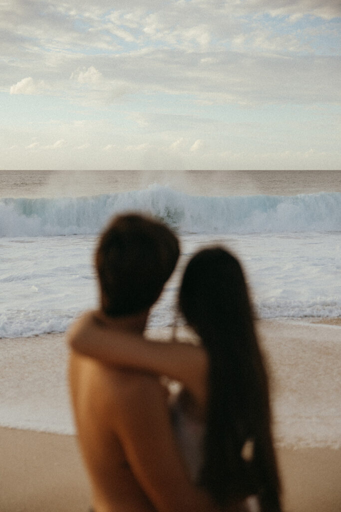 couple embraces looking at ocean waves at Hawaii photography content day
