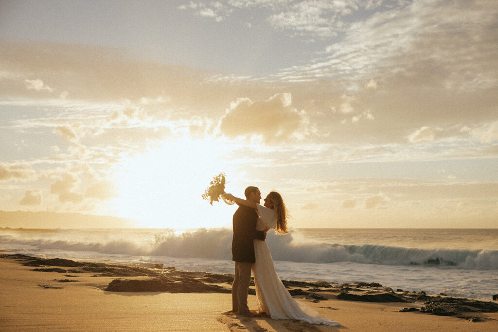 couple embraces at sunrise on beach at Hawaii photography content day
