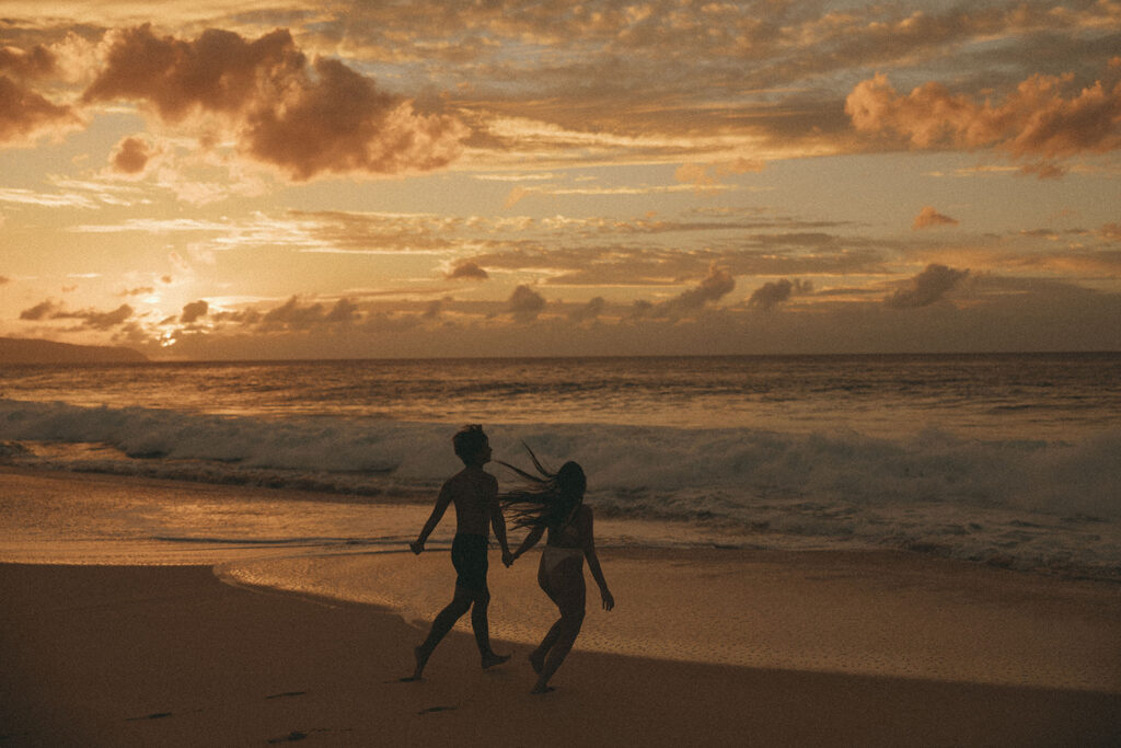 couple runs through beach at sunset during Hawaii photography content day