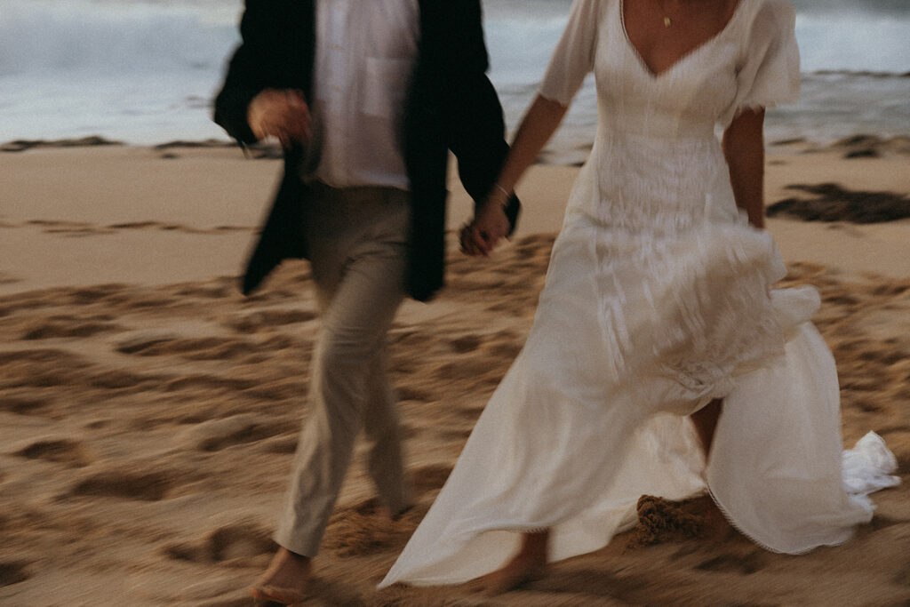 bride and groom holds hands walking through beach at Hawaii photography content day
