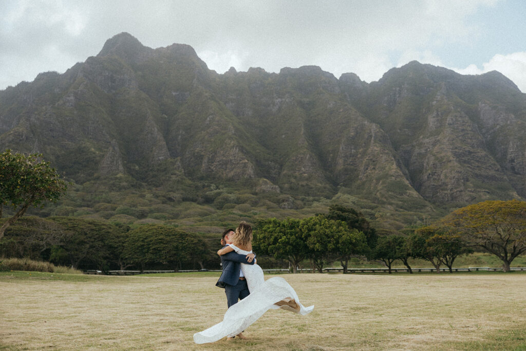 couple twirls below mountains at Hawaii elopement