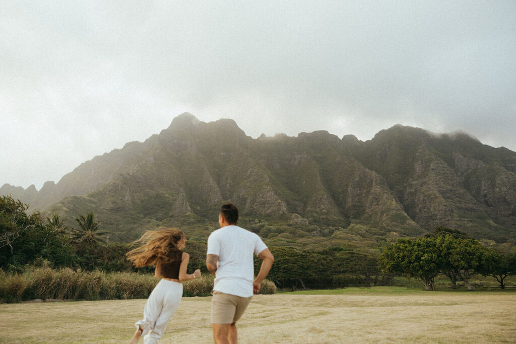 couple runs through field under foggy mountains at Hawaii photography content day
