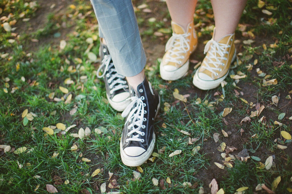 couple wear different colored chuck taylor shoes
