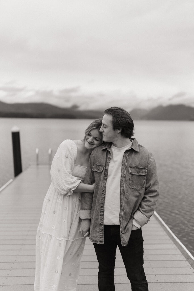 couple embraces on pier at lake in  Glacier National Park 