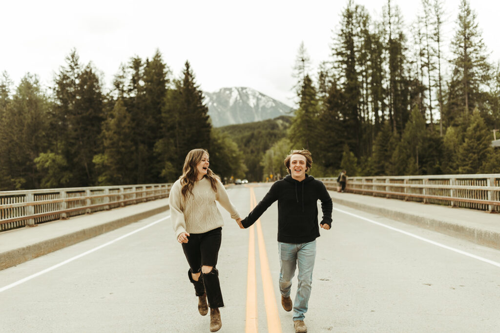 couple runs along road holding hands at Glacier National Park engagement session