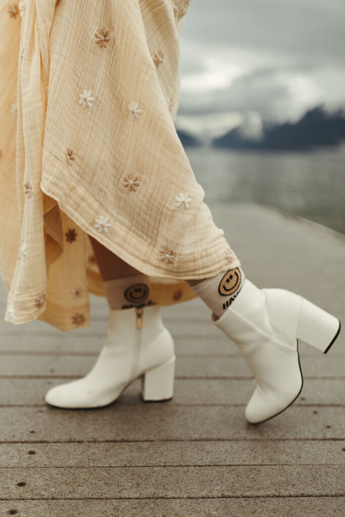 bride wears white boot with smiley face socks at Glacier National Park engagement session