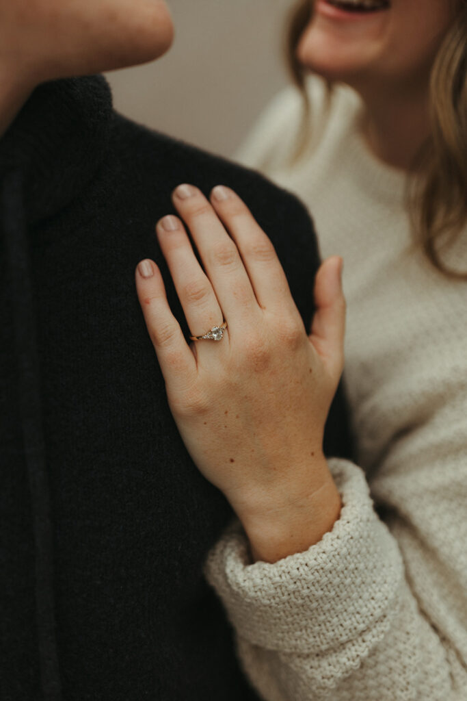 bride holds groom showing engagement ring at Glacier National Park engagement session