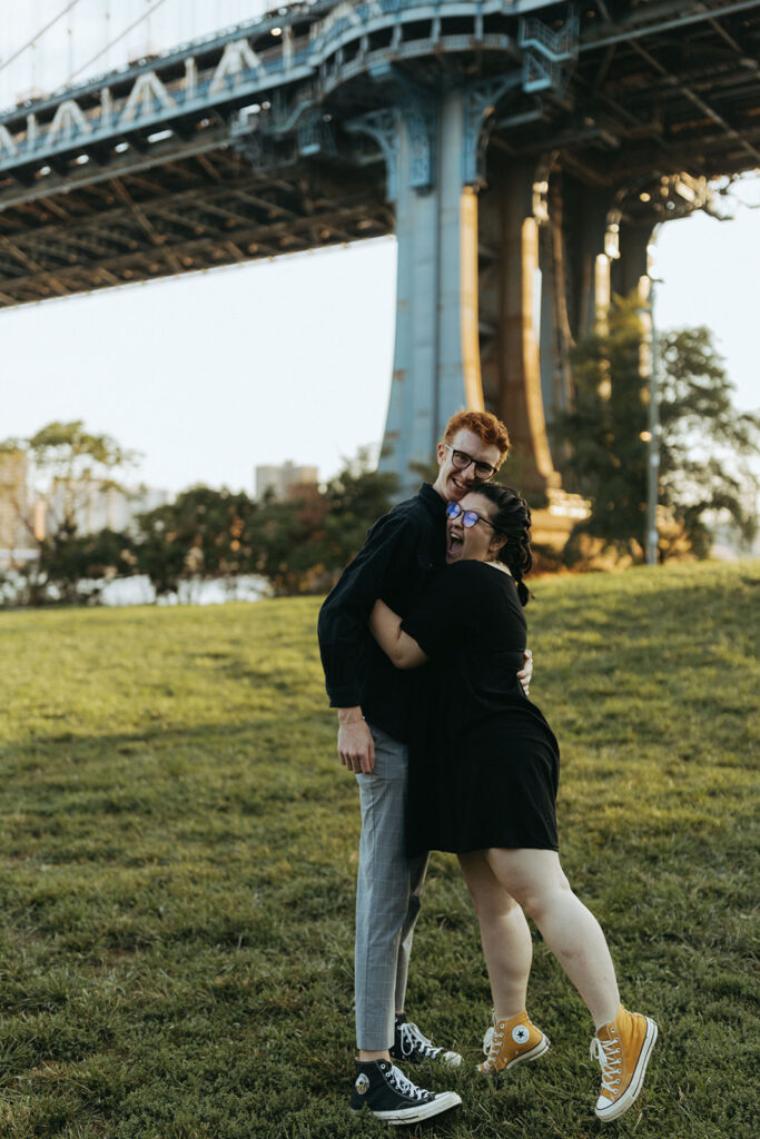 couple hugs after marriage proposal under Manhattan bridge