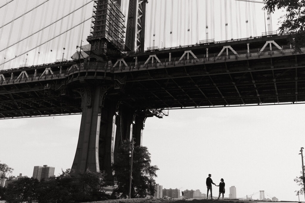 couple holds hands standing under Manhattan bridge using marriage proposal ideas