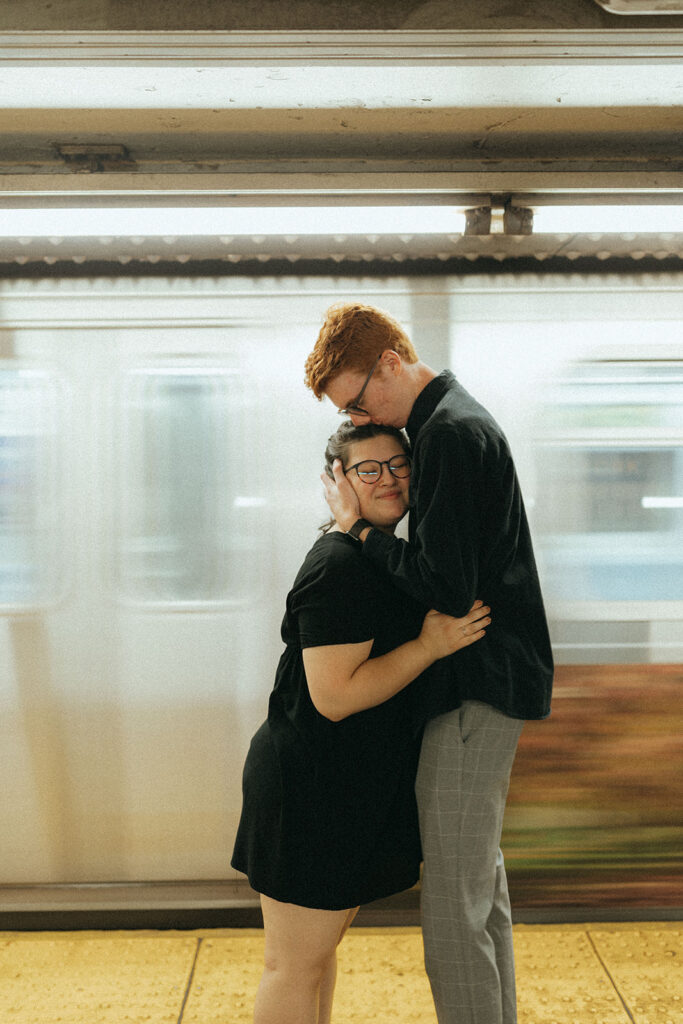 couple kisses in front of new york subway train 