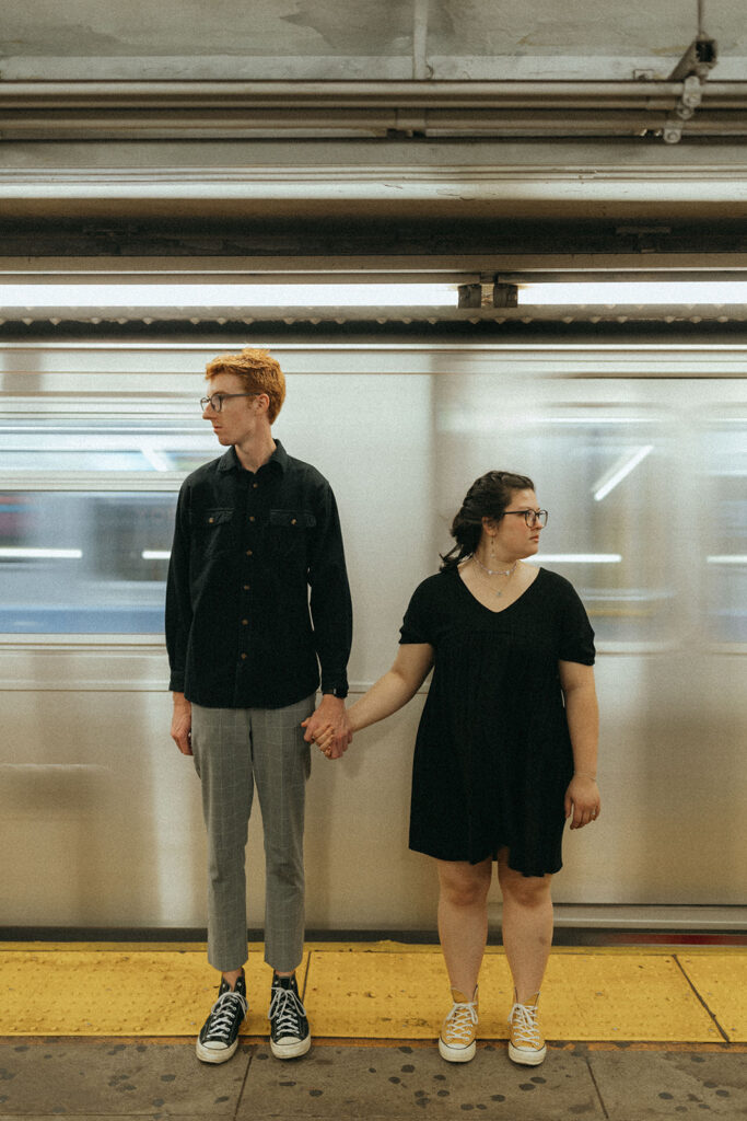 couple holds hands beside new york city subway 