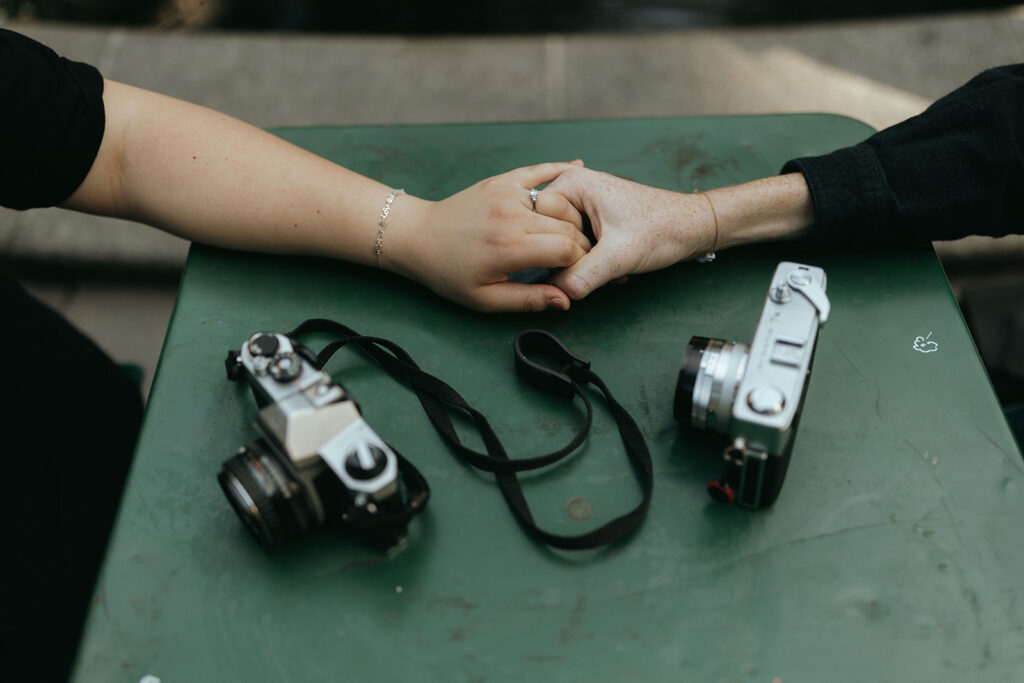 couple holds hands beside film cameras