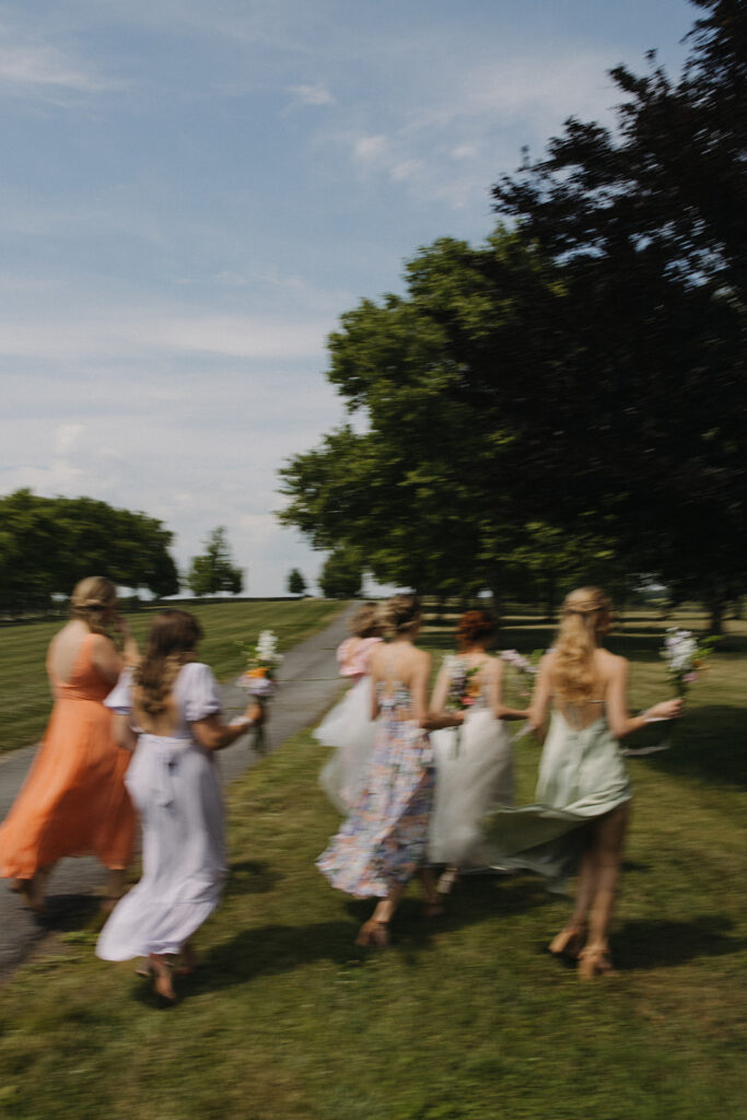 bride walks with bridesmaids holding wedding bouquets at garden party wedding
