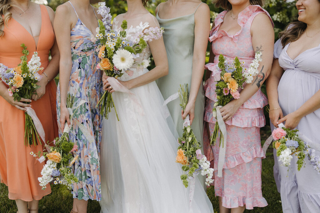 bride holds wedding bouquets with bridesmaids at garden party wedding
