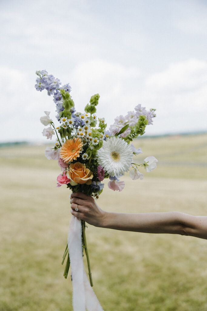 bride holds wedding wildflower bouquet at garden party wedding