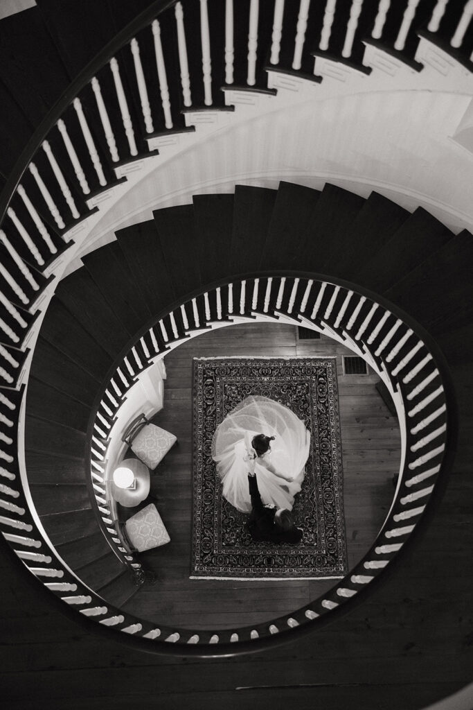 couple stands under spiral staircase in virginia wedding estate