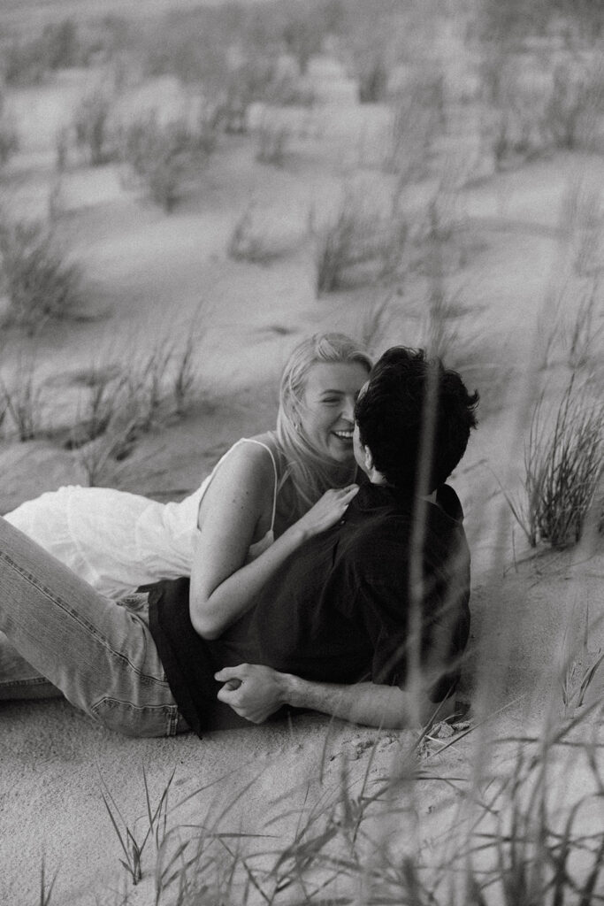 couple lies in the sand at Virginia Beach sunrise engagement photos
