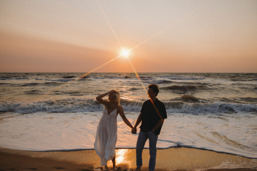 couple walks holding hands at Virginia Beach sunrise engagement photos
