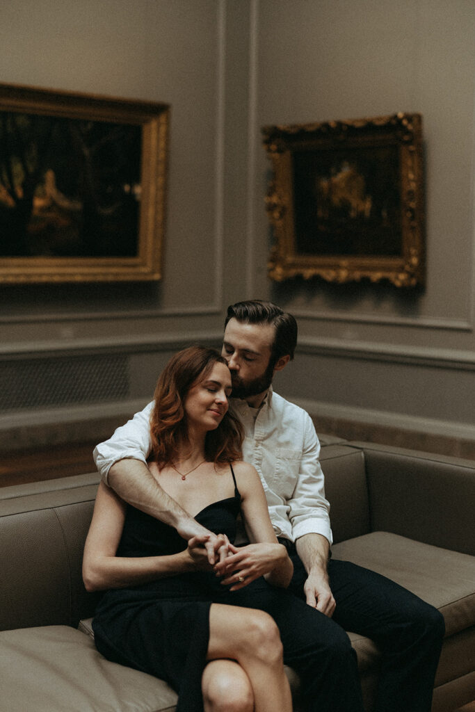 groom kisses bride's forehead at art gallery engagement session