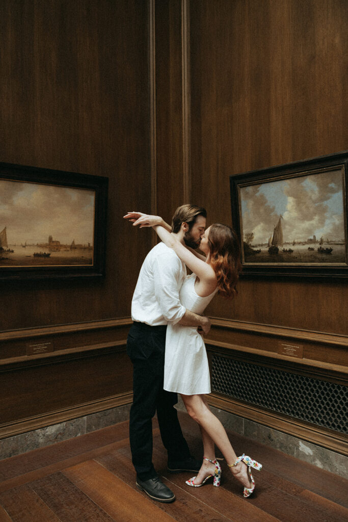 couple kisses at art gallery engagement session