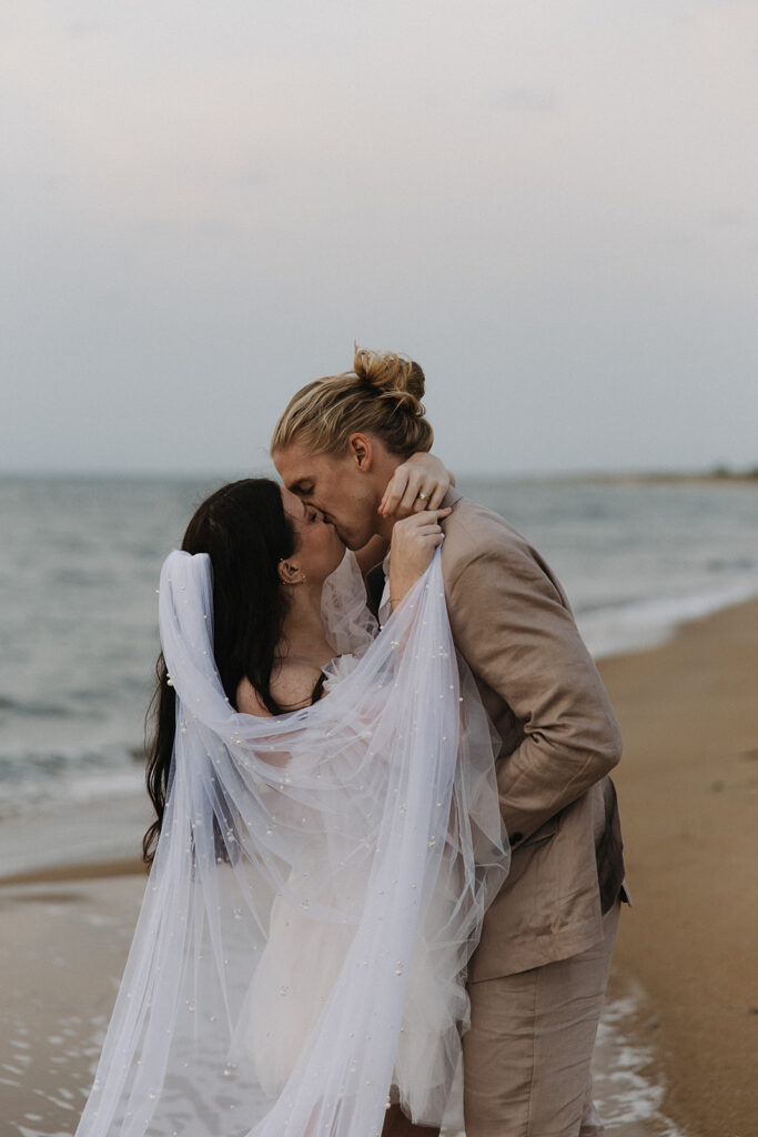 couple kisses under pearl-studded wedding veil