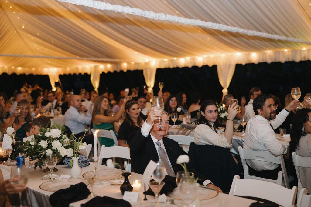 guests cheer at outdoor wedding with tent