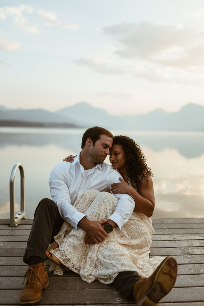 couple sits together on pier at Lake McDonald Glacier National Park