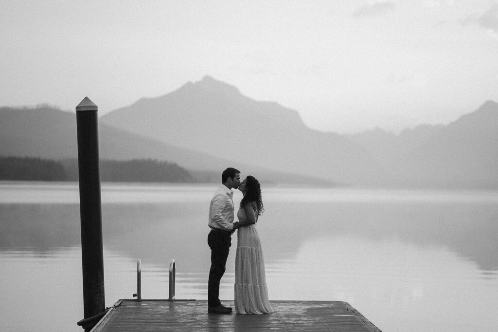 couple kisses on pier at Lake McDonald Glacier National Park