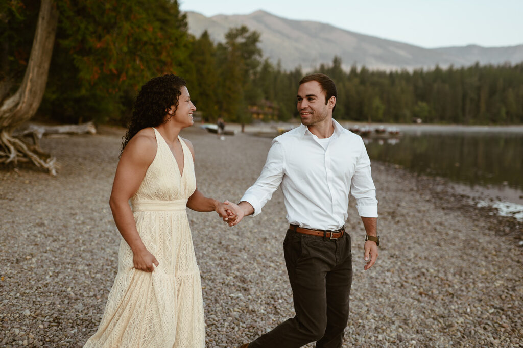 couple walks holding hands at Lake McDonald Glacier National Park