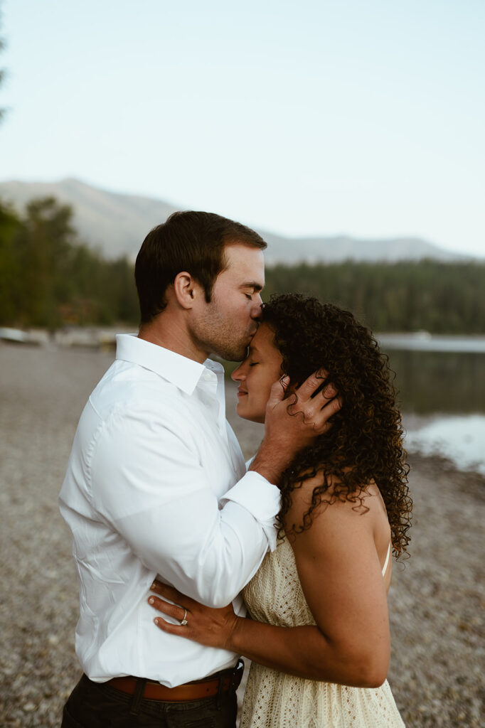 couple kisses at lakeside engagement