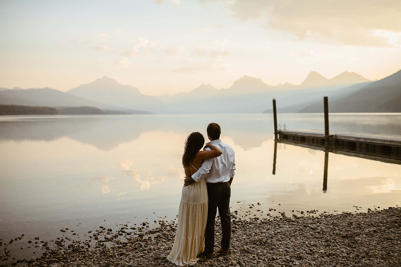 couple embraces at sunrise Lake McDonald Glacier National Park engagement