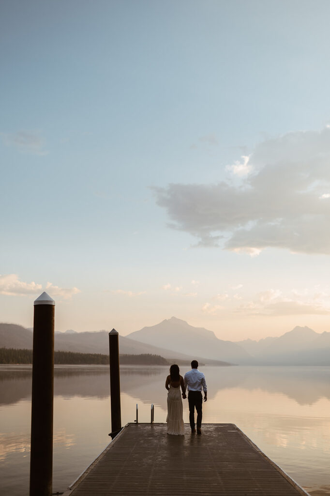 couple holds hands on pier at Lake McDonald Glacier National Park