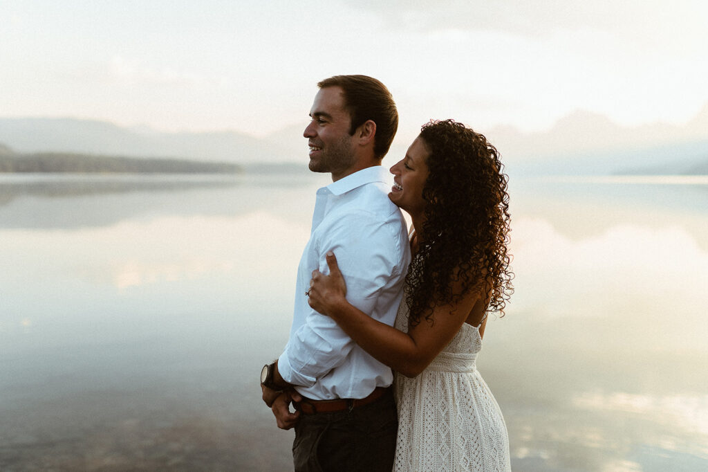 couple embraces at sunrise lake engagement session