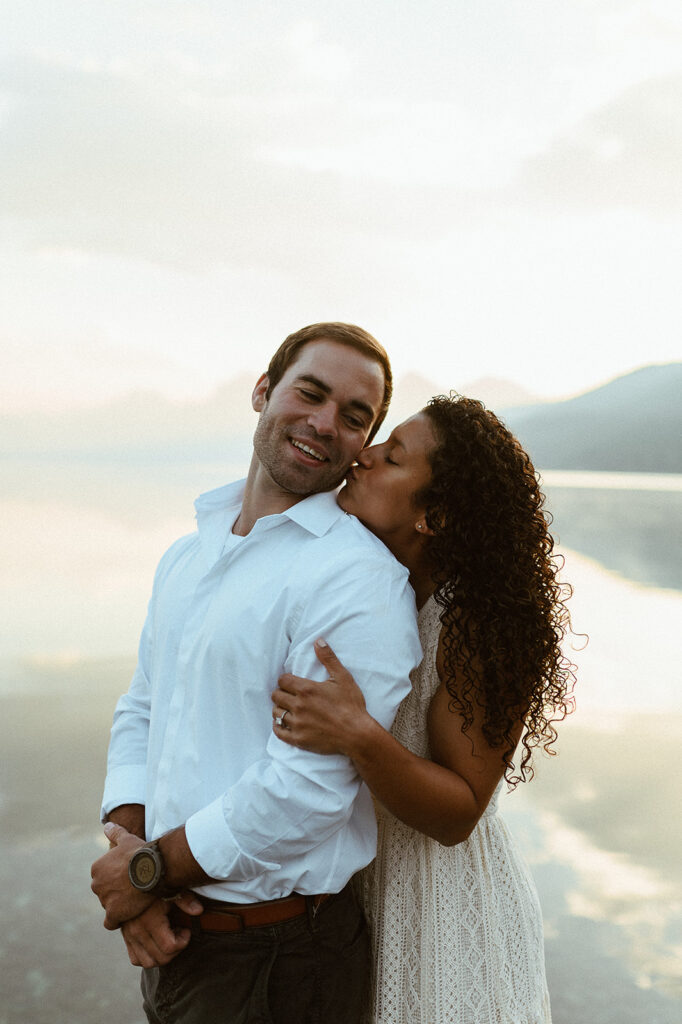 couple kisses at sunrise lake engagement session