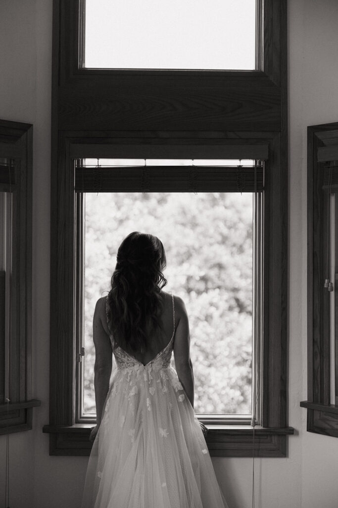 bride looks out window at wedding reception in backyard