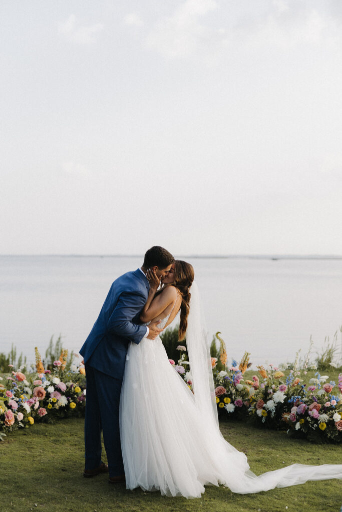 couple kissed beside wedding flowers