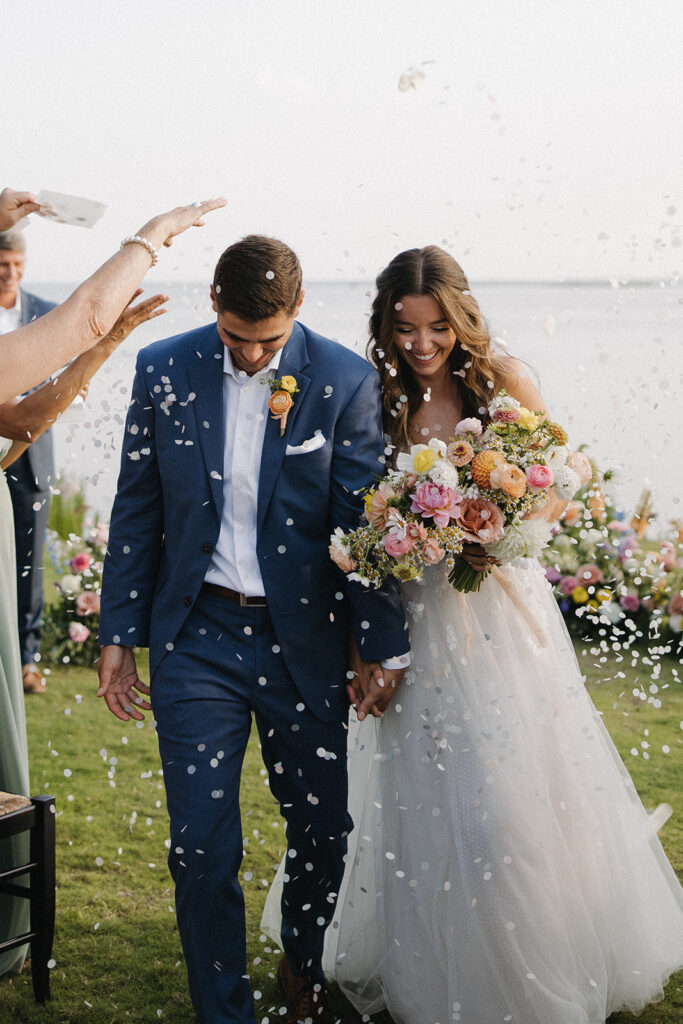 couple exits wedding walking through flower petals