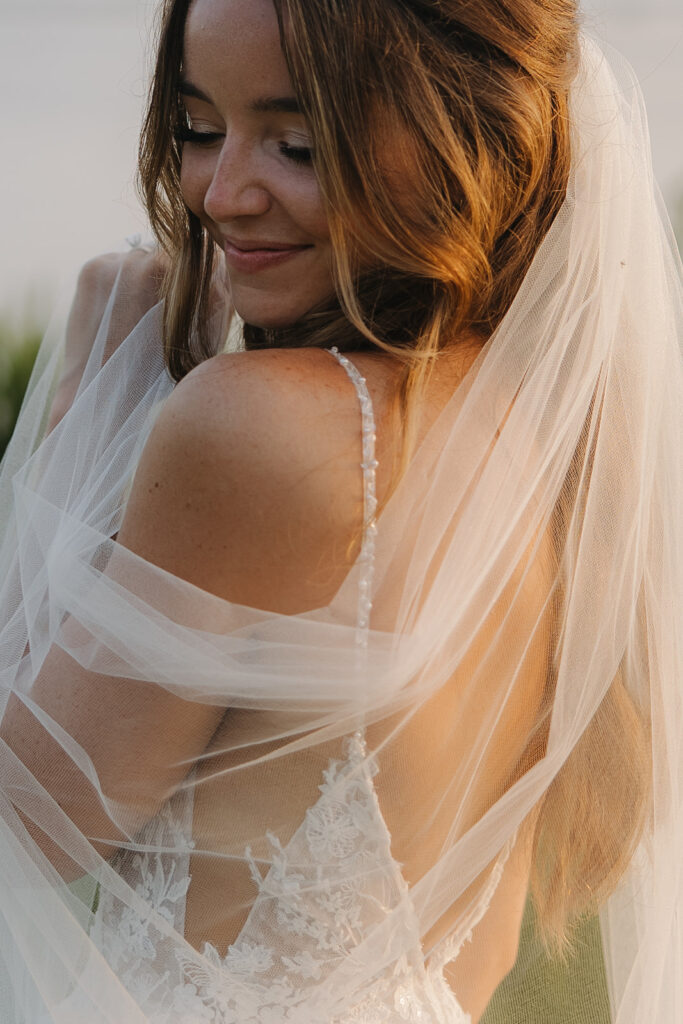 bride wraps herself in white wedding veil