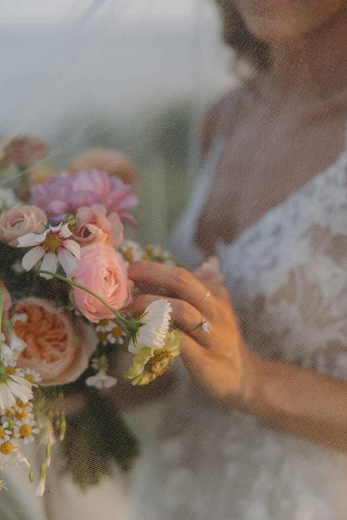 bride holds wedding bouquet under veil