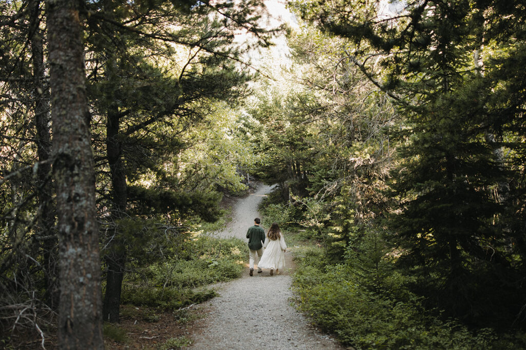 couple walks through Glacier National Park forest 