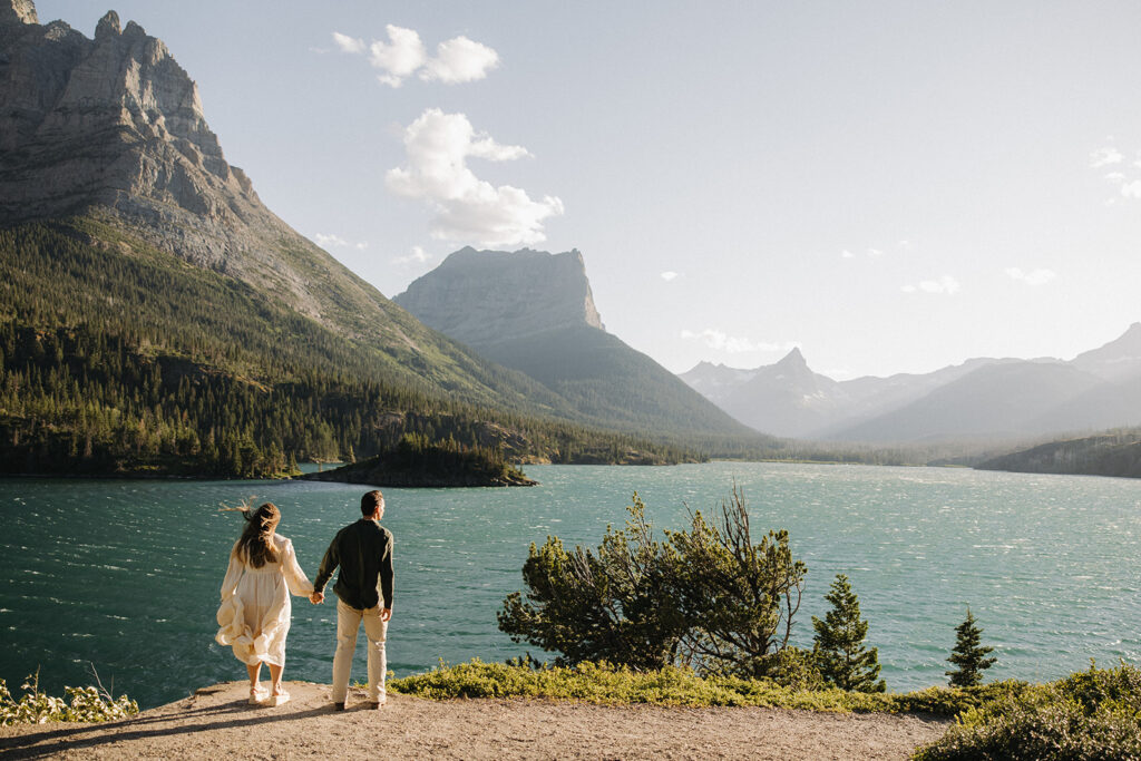 couple holds hands at windy Glacier National Park engagement
